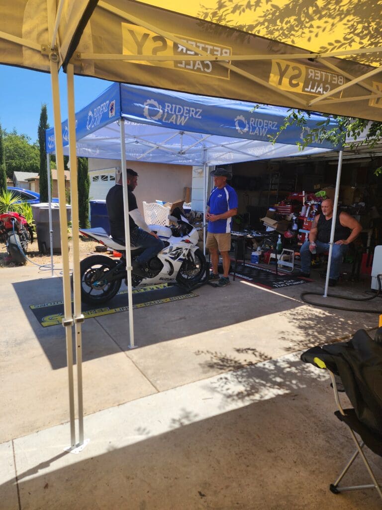 A group of people standing around a motorcycle under a tent.