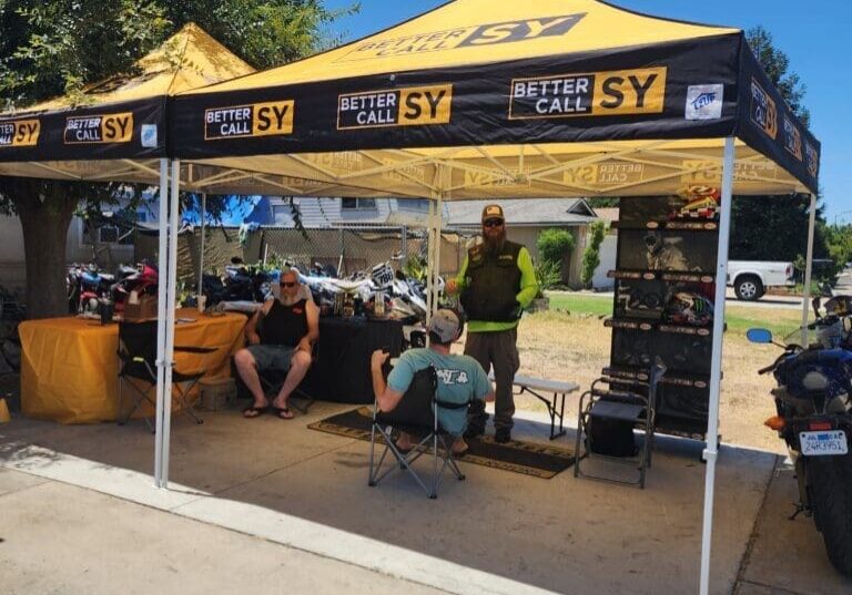 Yellow promotional canopy tent with people and motorcycles